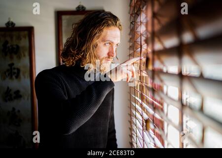 Uomo maturo che guarda fuori finestra Foto Stock