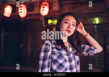 Donna etnica camminare sulla strada notturna in città Foto Stock