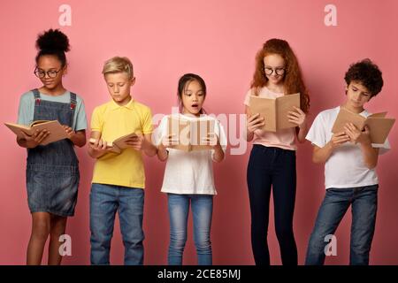 Ha messo a fuoco diversi ragazzi che leggono libri su sfondo rosa Foto Stock