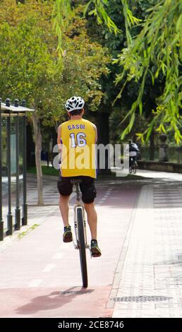 Unicyclist su una pista ciclabile in estate sole con un Numero della maglia da basket Pau Gasol Yellow Lakers 16 vista posteriore a Burgos Spagna Foto Stock