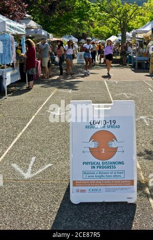Agosto 2020: Mercato del sabato a Salt Spring Island, British Columbia, cartello che dice alle persone di praticare il distanziamento fisico a causa della pandemia di Covid 19 Foto Stock