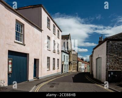 Il sole splende sulle vecchie case tradizionali di High Street ad Axminster, Somerset. Foto Stock