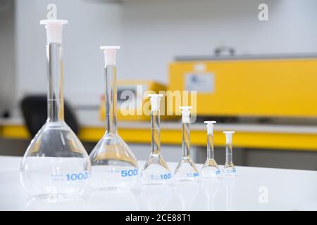 Vari matracci di vetro posti in fila sul tavolo e preparati per esperimenti in laboratorio moderno Foto Stock