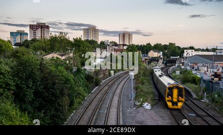 Un treno passeggeri di classe 158 arriva alla stazione di Lawrence Hill accanto al paesaggio urbano della tenuta Barton Hill council di Bristol. Foto Stock