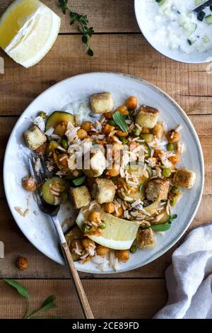 Vista dall'alto di una deliziosa insalata sana con riso e grigliata tofu e verdure servite in ciotola su tavolo di legno Foto Stock