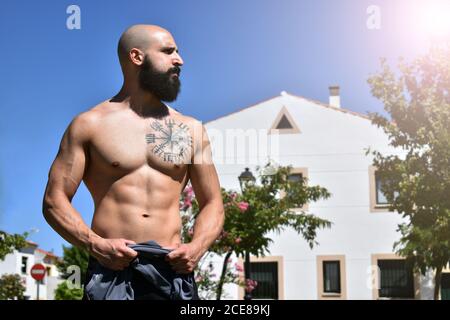 Fitness uomo muscolare in piedi e mostrando i suoi muscoli in un parco pubblico con luce e molto spazio la destra Foto Stock