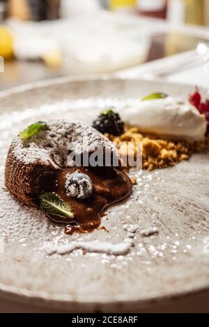 Gustosa torta di lava al cioccolato con mirtillo e menta piatto sul tavolo da caffè Foto Stock