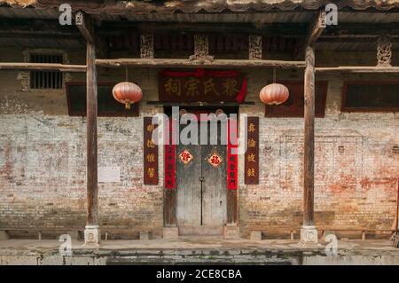 Esterno di un vecchio edificio in pietra con pareti in shabby e ornamentale Porta con lanterne di carta nella contea di Yangshuo Foto Stock