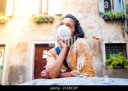 Giovane donna che indossa la maschera facciale che si affaccia in una strada di Venezia in Italia. Viaggi e turismo industria durante la pandemia del virus della corona e covid19 d Foto Stock