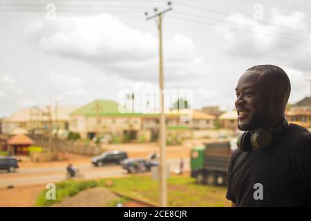 Giovane uomo africano in piedi all'esterno con cuffie wireless Foto Stock