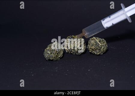 Siringa e palline di tè su una superficie nera Foto Stock
