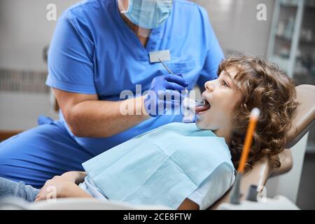 Bambino allegro seduto su una sedia dentale durante il check-up Foto Stock