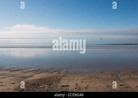 Nuvole nel cielo blu riflesse sulla spiaggia di sabbia in basso marea Foto Stock