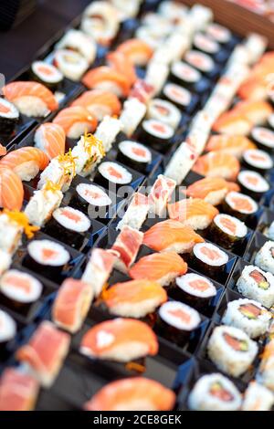 Alto angolo di sushi e panini assortiti e appetitoso contenitori in plastica in negozio Foto Stock