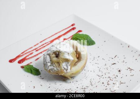 gustosa mela al forno con noce, sciroppo e menta su piatto isolato Foto Stock