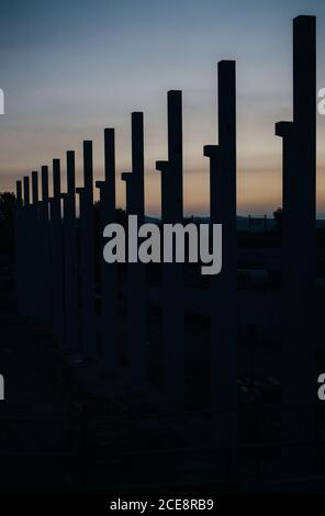 silhouette di cantiere con gru e colonne al tramonto Foto Stock