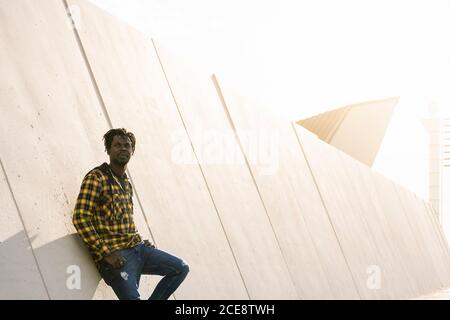 giovane africano appoggiato su una moderna struttura in cemento al tramonto, stile di vita concetto Foto Stock