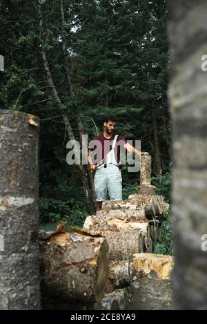 Il viaggiatore maschile adulto taglia i boschi in piedi contro lussureggianti boschi scuri A New Brunswick Foto Stock