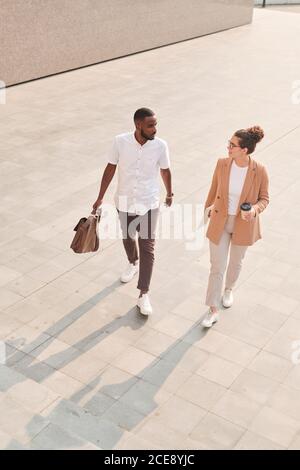 Vista al di sopra dei giovani colleghi multietnici che discutono di questioni di lavoro spostarsi mentre si è in ufficio Foto Stock