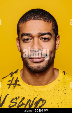 Razza mista giovane uomo che guarda la macchina fotografica con espressione seria su sfondo giallo Foto Stock