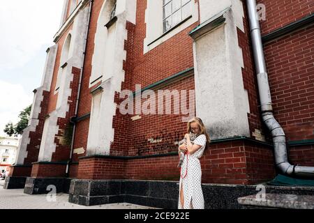 Giovane donna che tiene un gatto scozzese diritto sulla strada vicino a un edificio architettonico. Foto Stock