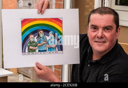 L'artista e illustratore di cartoni animati Graeme Bandeira al lavoro nel suo studio di casa che tiene uno dei suoi cartoni animati di ispirazione NHS. Foto Stock