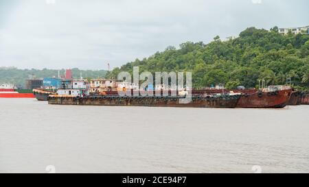 Alcune vecchie chiatte arrugginite sono a ormeggio in un porto di Goa, India. Foto Stock
