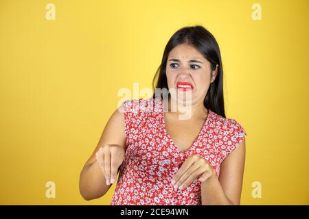 Giovane bella donna su isolato sfondo giallo disgustava espressione, dispiaciuto e pauroso fare faccia disgusto perché reazione di avversione. Con Foto Stock