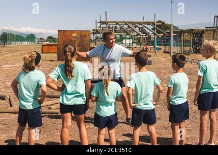 Allenatore di fitness maschile che dà istruzioni ai bambini a un bootcamp Foto Stock