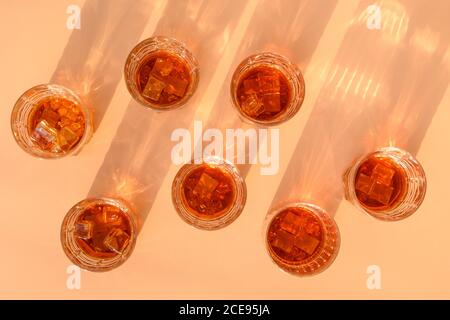 Molti bicchieri di whisky freddo serviti in rocce su sfondo beige. Foto Stock