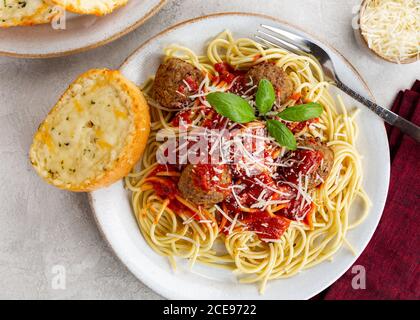 Sovrastante la cena con spaghetti e polpette con pane tostato al formaggio su una piastra Foto Stock