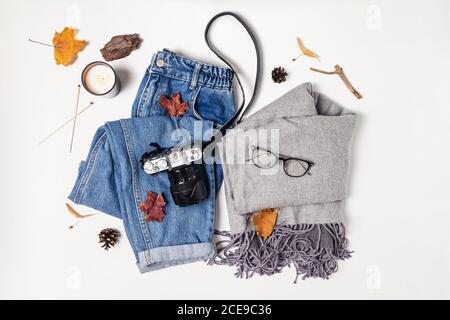 Abbigliamento femminile, macchina fotografica e foglie gialle sul tavolo bianco Foto Stock