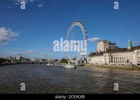 Vista panoramica sul Tamigi con la ruota panoramica London Eye e la County Hall contro il cielo blu in estate, Londra, Inghilterra, Regno Unito Foto Stock