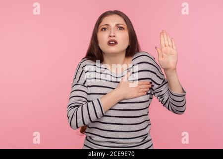 Giuro! Ritratto di donna molto responsabile e onesta in felpa a righe dando promessa, facendo voto solenne nella tradizione cerimoniale con raised han Foto Stock