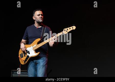 L'uomo caucasico sta suonando sul palco. Bella persona maschile sta giocando su Bass Guitar al Concert. Foto Stock