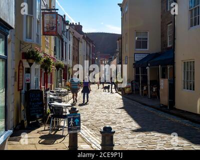 Persone in Staithes High Street, che fa parte del percorso a piedi lungo distanza Cleveland Way, in un sole estate Bank Holiday pomeriggio Foto Stock