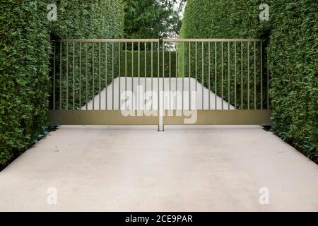 Vialetto in cemento con cancello metallico chiuso in un quartiere residenziale Foto Stock