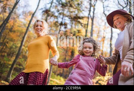 Bambina con madre e nonna in una passeggiata nella foresta d'autunno. Foto Stock