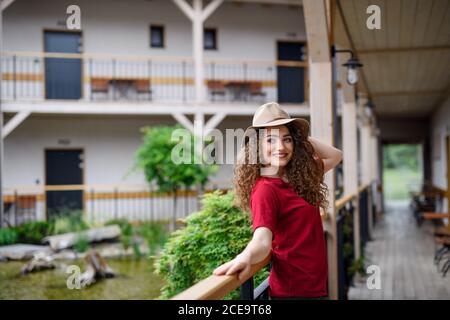 Giovane donna in piedi all'aperto in hotel in vacanza, rilassante. Foto Stock