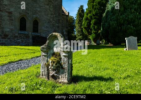 Vecchia tomba indossata con cranio e crossone nel cortile del villaggio, Humbie Parish Church, East Lothian, Scozia, Regno Unito Foto Stock