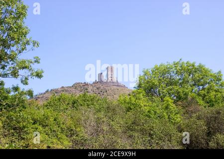 Ruines del castello di Hazmburk in cima alla cima della catena montuosa di ceske stredohori. Alberi da frutta e cielo blu. Foto Stock
