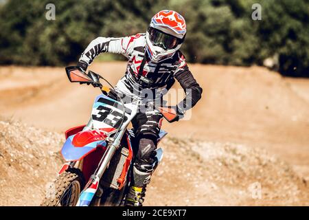 uomo irriconoscibile in casco che guida moto moderna in campagna strada in giornata di sole durante la gara Foto Stock