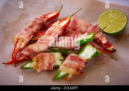 Popper Jalapeno avvolti in pancetta ripiena di formaggio condito con erbe e spezie, vista dall'alto. Profondità dof. Foto Stock