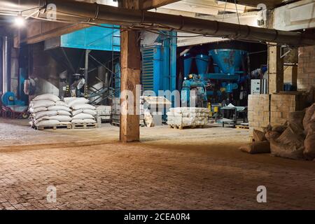 interno semi-scuro dell'officina di lavorazione del legno con attrezzatura e imballaggio di prodotti - tavole e trucioli Foto Stock