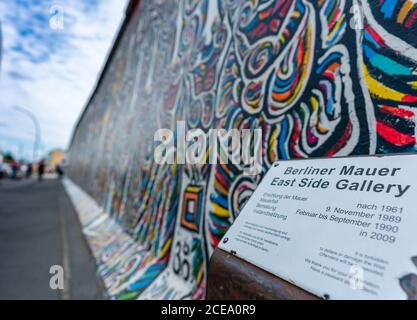 Berlino, Germania - 25 agosto 2020: Vista di un murale sul Muro di Berlino presso la famosa East Side Gallery con targa informativa Foto Stock