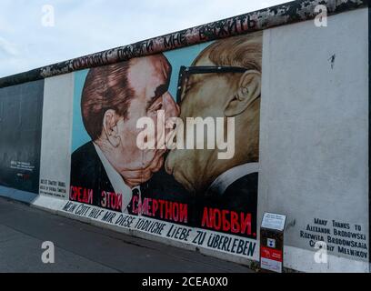 Berlino, Germania - 25 agosto 2020: Vista di un murale sul Muro di Berlino presso la famosa East Side Gallery con targa informativa Foto Stock