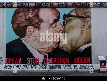 Berlino, Germania - 25 agosto 2020: Vista di un murale sul Muro di Berlino presso la famosa East Side Gallery con targa informativa Foto Stock