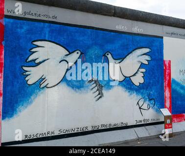 Berlino, Germania - 25 agosto 2020: Vista di un murale sul Muro di Berlino presso la famosa East Side Gallery con targa informativa Foto Stock