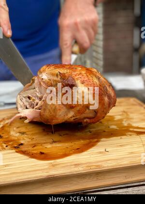 Uomo che taglia il pollo arrosto sul tavolo all'aperto Foto Stock