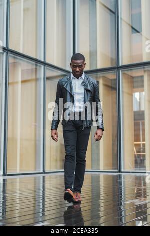 Uomo afro-americano di stile che cammina sul pavimento bagnato Foto Stock